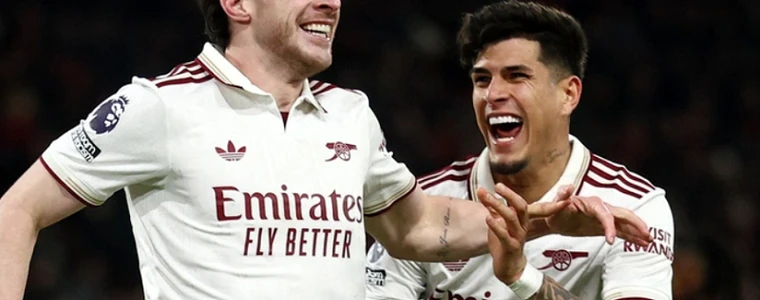 Chiếc cúp Siêu cúp Anh đặt trên sân cỏ Cardiff với dải màu đỏ Arsenal và xanh Man City hai bên trước trận đấu